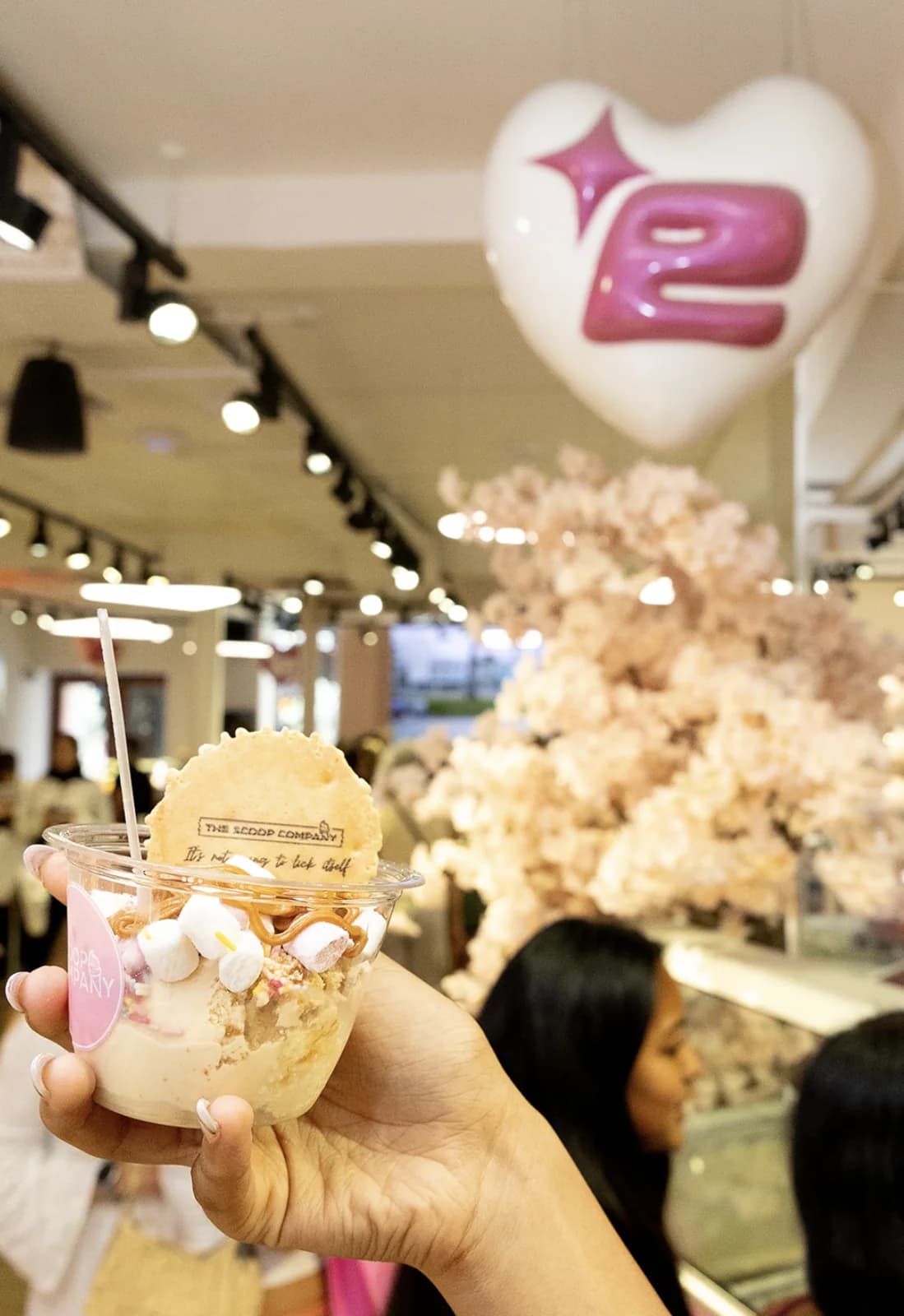 A Scoop cup of gelato with a branded wafer, held up under the Edikted heart balloon on Carnaby Street