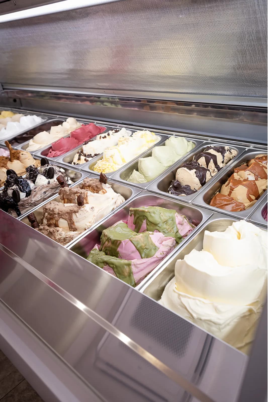 A full gelato cabinet, pans of pistachio, salted caramel, chocolate and vanilla