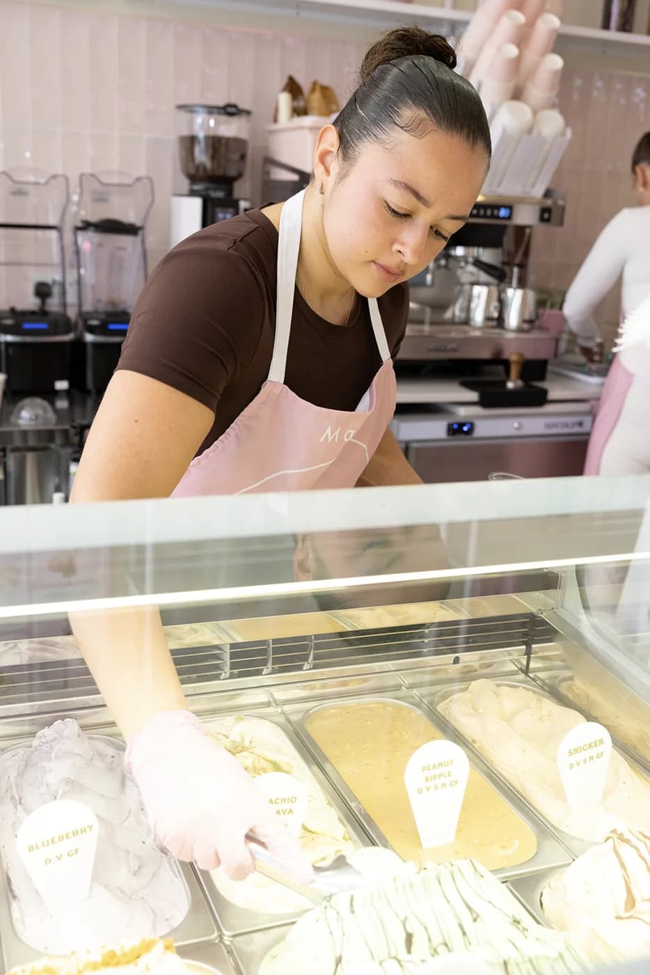 A team member scooping gelato from the counter in a Scoop apron