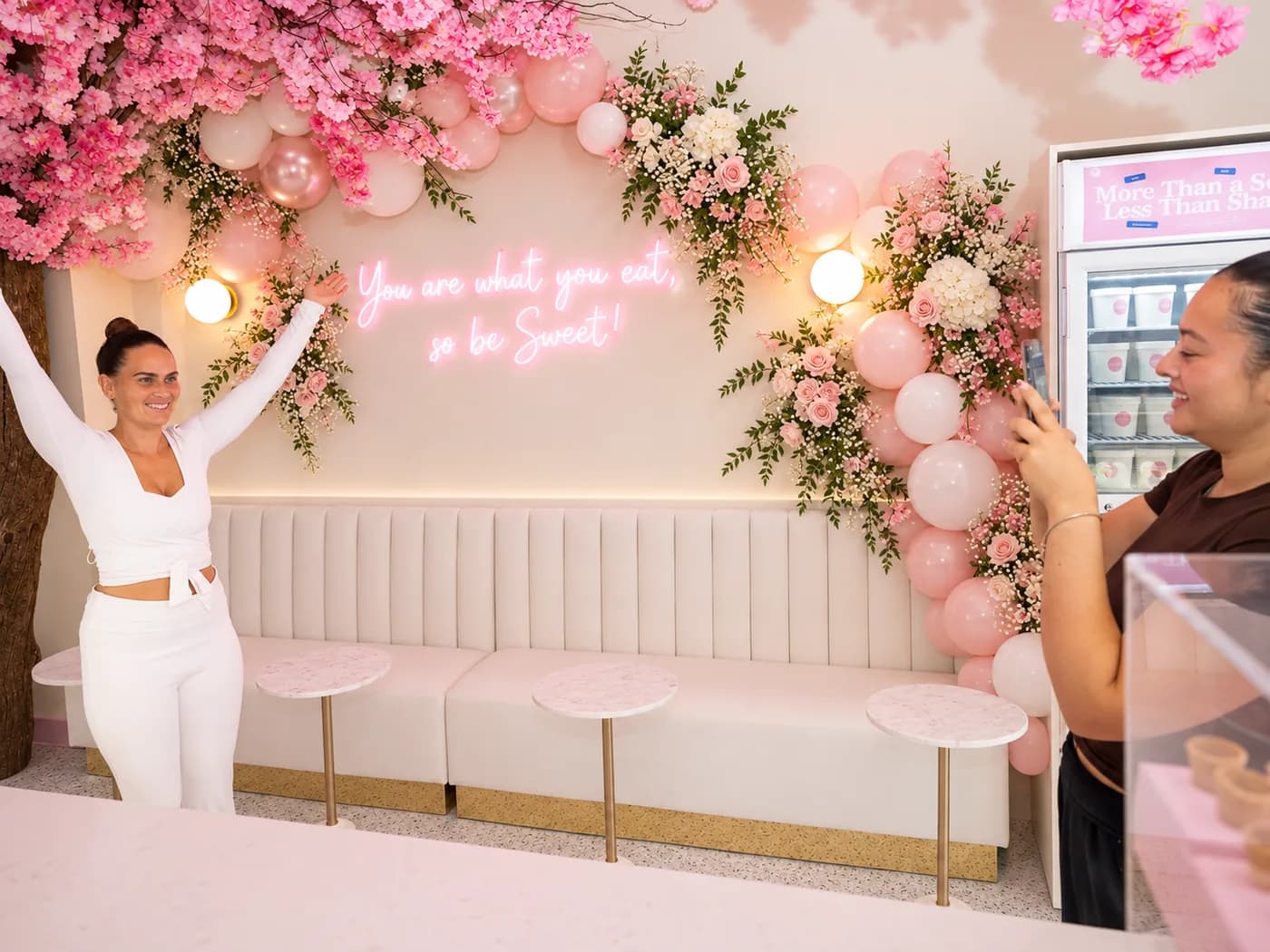 A guest photographed under the blossom arch and neon sign